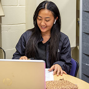 Student Studying in the Library with a Laptop.