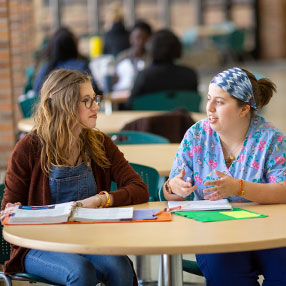 Two Nursing Students Sitting in the Cafeteria Studying.