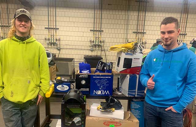 Welding students stand near prizes