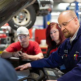 A Professor and Two Students Working on a Car in the Lab.