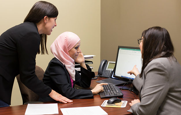 A Student Working with Two Advisors on a Computer. 