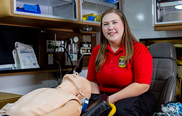 student in red polo uniform shirt in ems lab
