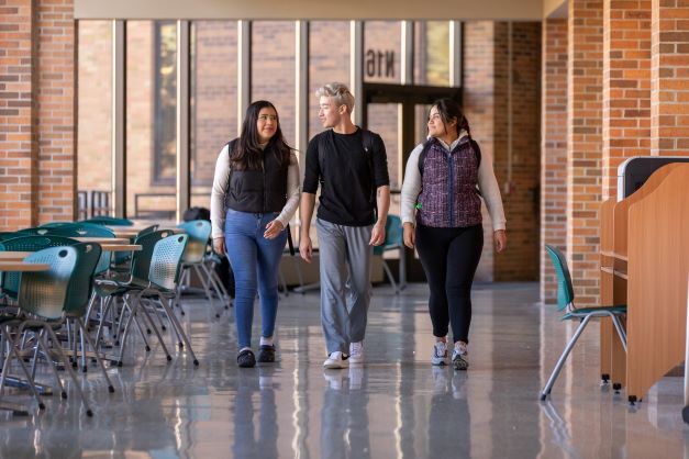 Three students walking in hallway on campus at Anoka Tech