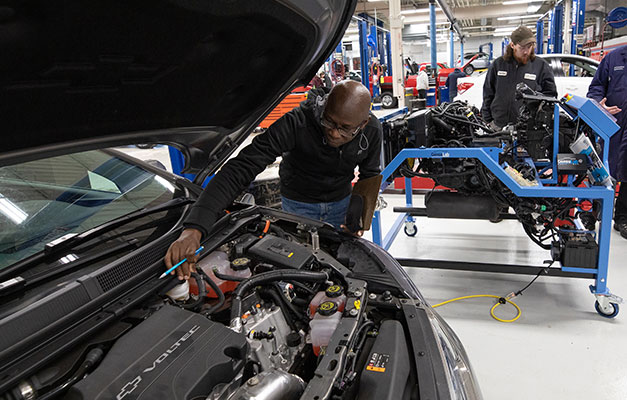 A Student Working on a Car in the Shop. 