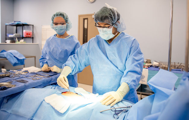 Surgical Technician Students Practicing on a Mannequin for a Test. 